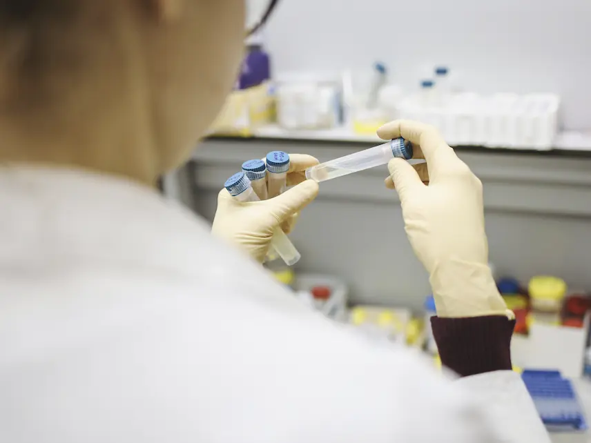 Female scientist in lab coat looking at a test tube